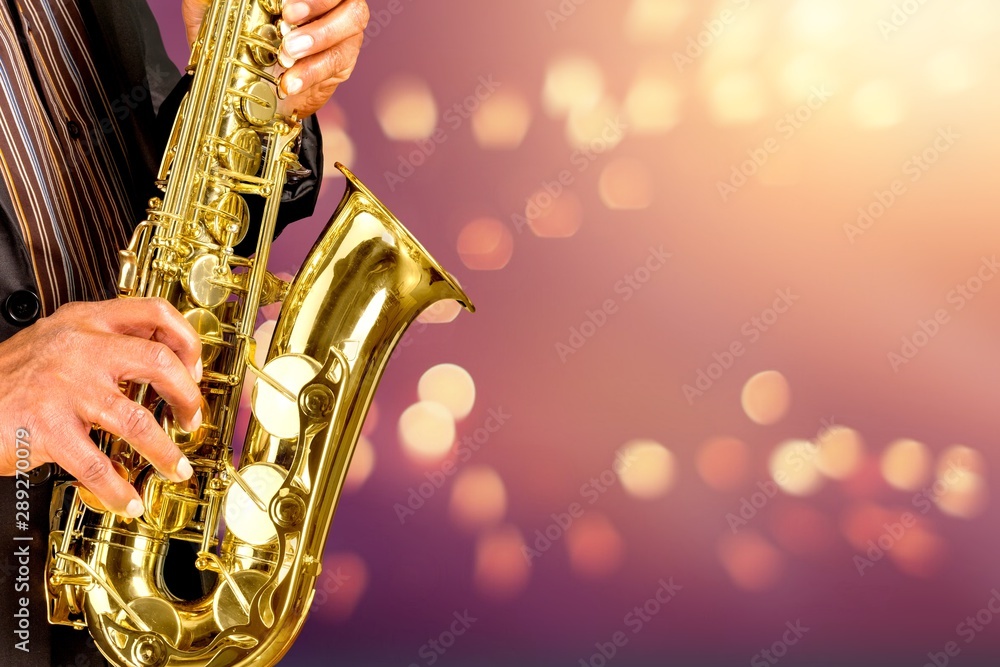 Fototapeta premium Close-up man playing on saxophone on blurred background