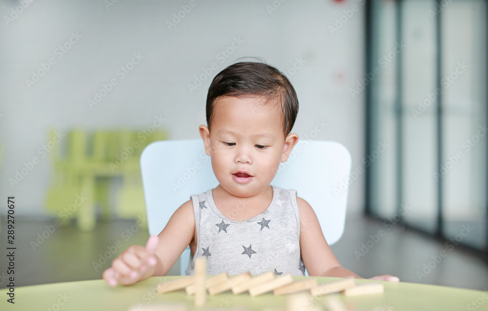 Happy little Asian baby boy playing wood blocks tower game for Brain and Physical development skill in a classroom. Focus at children face. Kid imagination and learning concept. Happy little Asian baby boy playing wood blocks tower game for Brain and Physical development skill in a classroom. Focus at children face. Kid imagination and learning concept.