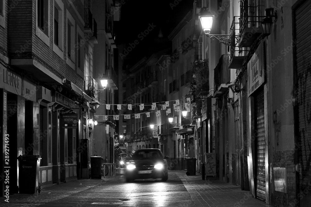 Escena nocturna en blanco y nego de un coche en una calle antigua
