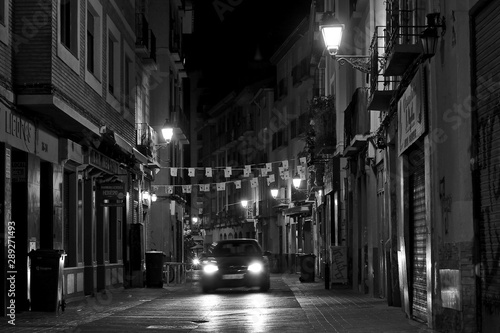 Escena nocturna en blanco y nego de un coche en una calle antigua photo