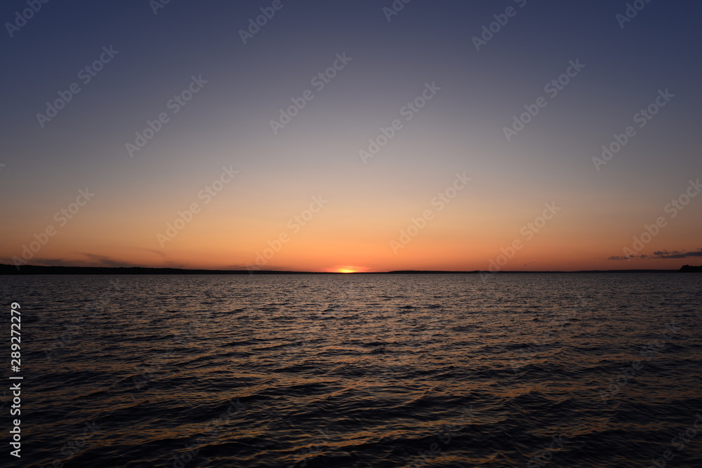 Sunset in the blue sky on the horizon with water wave pattern