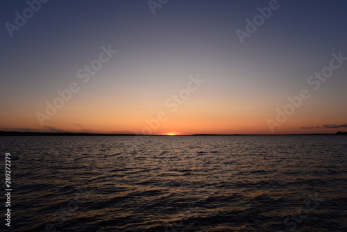Sunset in the blue sky on the horizon with water wave pattern © yarvin13