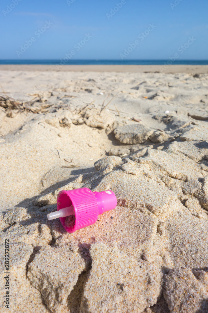 Pink spray cap on the beach sand. Plastic pollution of the oceans concept. Pink spray cap on the beach sand. Plastic pollution of the oceans concept.