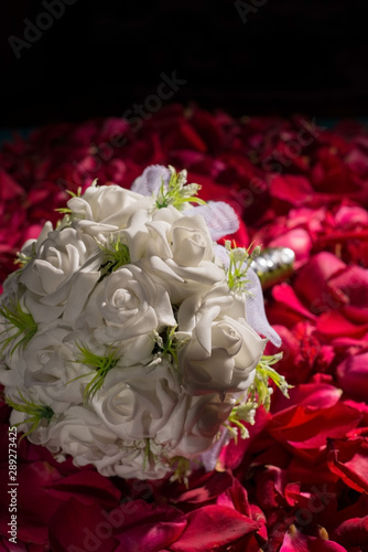 courtesy bouquet of white roses  against the background of red rose petals.