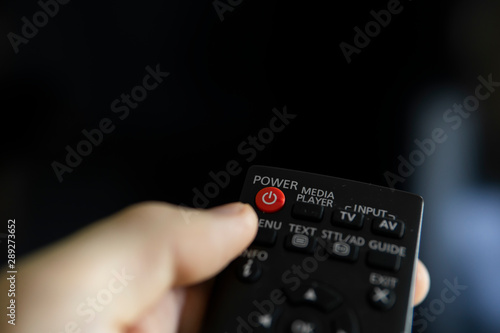 Close up on a man's hand with the remote control want switch on the TV and presses the button on the remote control. Remote control in hand closeup.