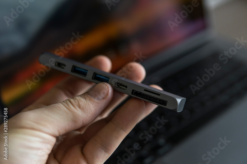 Man's hand holding The USB adapter under the Type-C connector for laptop. Multiport station for laptop with multiple different ports. USB to USB Type-C Hub Converter.