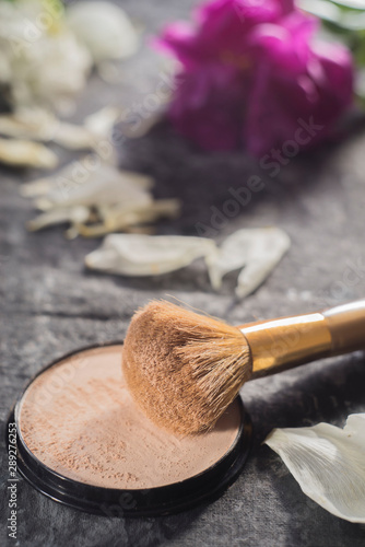 cosmetic powder for women, with pink and white peony petals, on an abstract black and white background, in warm colors photo