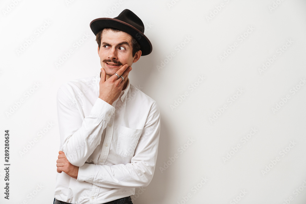 Image closeup of elegant mustached man wearing hat looking aside and touching his chin Image closeup of elegant mustached man wearing hat looking aside and touching his chin