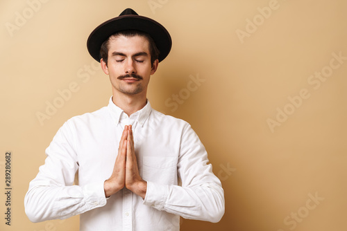 Image closeup of concentrated mustached man wearing shirt holding palms together with closed eyes