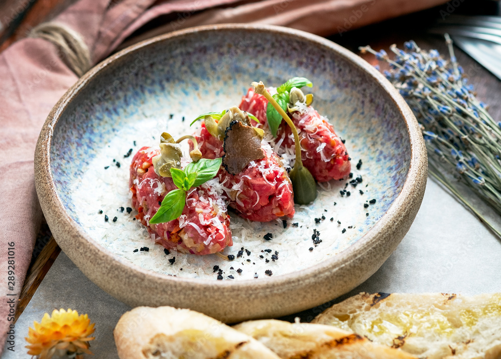 Beef tartare with mushrooms, truffle and capers on a plate. Serving in the restaurant, Haute cuisine