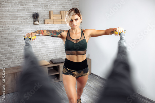 Attractive sporty young blonde woman workout with stretch bands in gym.