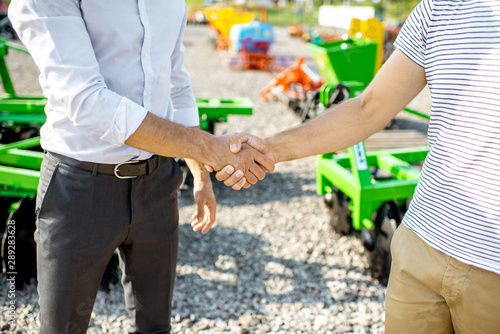 Cuadro en lienzo Buyer shaking hand with salesman on the open ground of the agricultural shop, ha