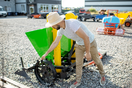 Agronomist choosing a new planter for farming at the outdoor ground of the shop with agricultural machinery