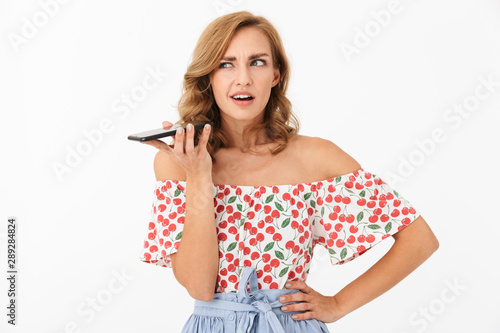 Portrait of caucasian puzzled woman wearing summer clothes holding smartphone and looking aside