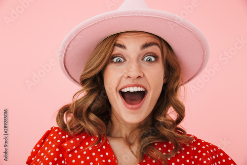 Emotional surprised young woman posing isolated over pink wall background.