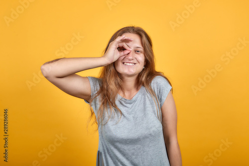 brunette girl in gray t-shirt over isolated orange background shows emotions