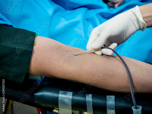 A nurse using needle to drawing a blood from donor s arm 