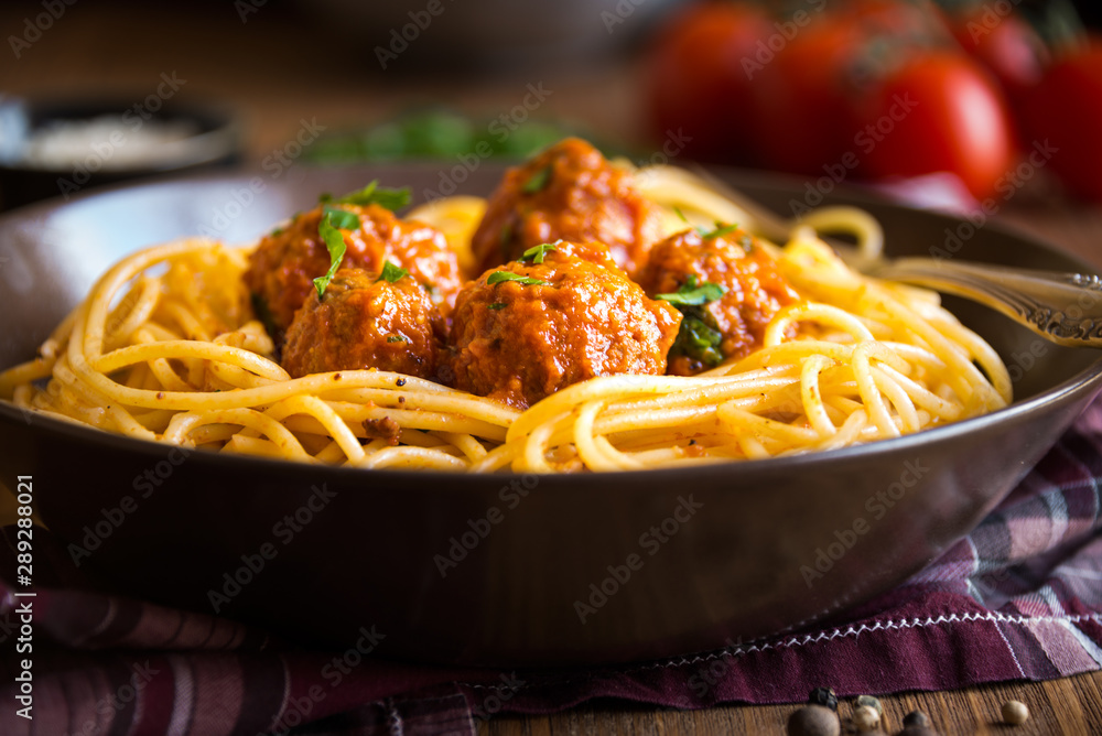 Fototapeta premium Delicious spaghetti with meatballs in tomato sauce on dark background, italian cuisine