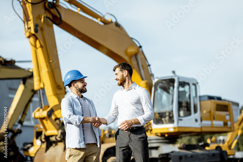 Фотография Builder choosing heavy machinery for construction, talking with a sales consulta