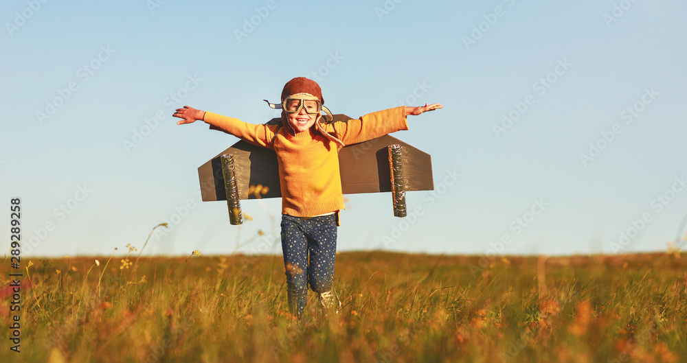 Child pilot aviator with wings of airplane dreams of traveling in summer  at sunset - obrazy, fototapety, plakaty 