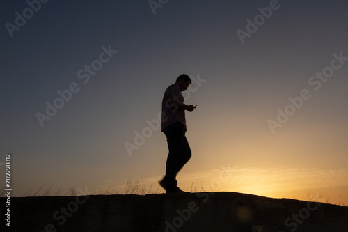 Fototapeta Naklejka Na Ścianę i Meble -  silhouette of man with cell phone at sunset