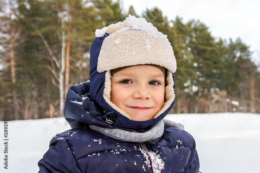 Obraz premium close up portrait of a happy child boy throws snow, snowflakes in the air in cold winter against the background of snowdrifts