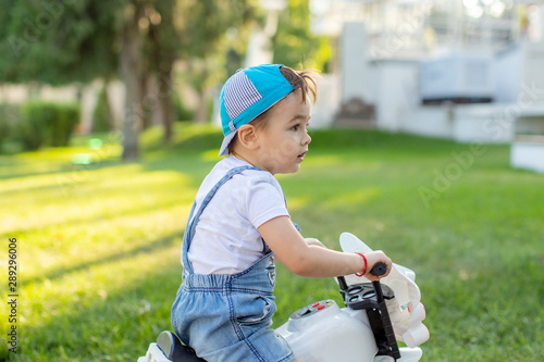 cute little biker on road with motorcycle. Young boy on toy motorcycle.little boy learn to ride first bike in nature