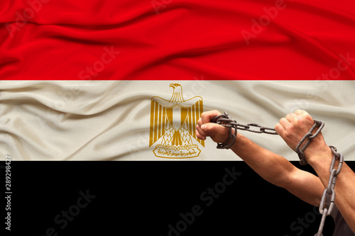 male hands of a prisoner in iron chains against the background of the national flag of the state of Egypt, the concept of political repression, crime, imprisonment, violation of human rights and freed photo