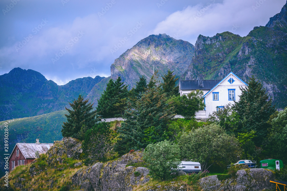Photo of picturesque mountainous area with vegetation, houses, cloudy sky in Norway on summer