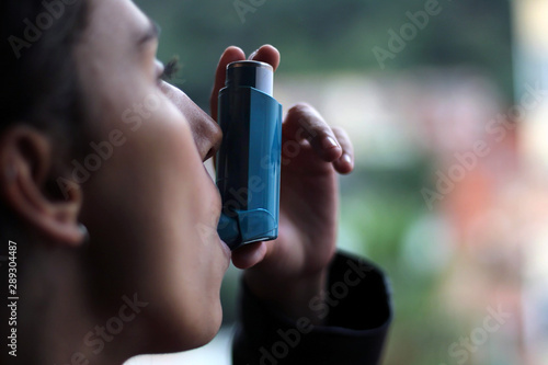 Health and medicine - Young girl using blue asthma inhaler to prevent an asthma attack. photo