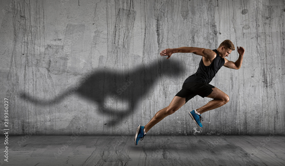 Athletic man sprinter running on dark wall background - obrazy, fototapety, plakaty 