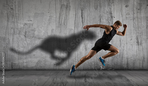 Athletic man sprinter running on dark wall background