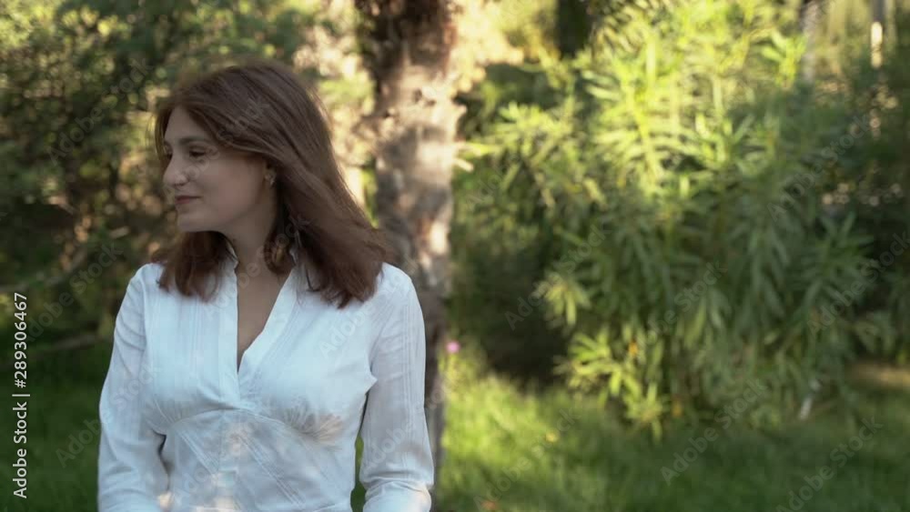 Beautiful girl close-up. Girl posing for the camera in a white shirt in the park. Lush hair. 4k Beautiful girl close-up. Girl posing for the camera in a white shirt in the park. Lush hair. 4k
