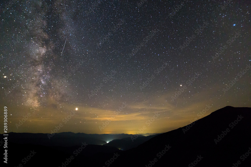 Night landscape of mountains with stars covered sky .