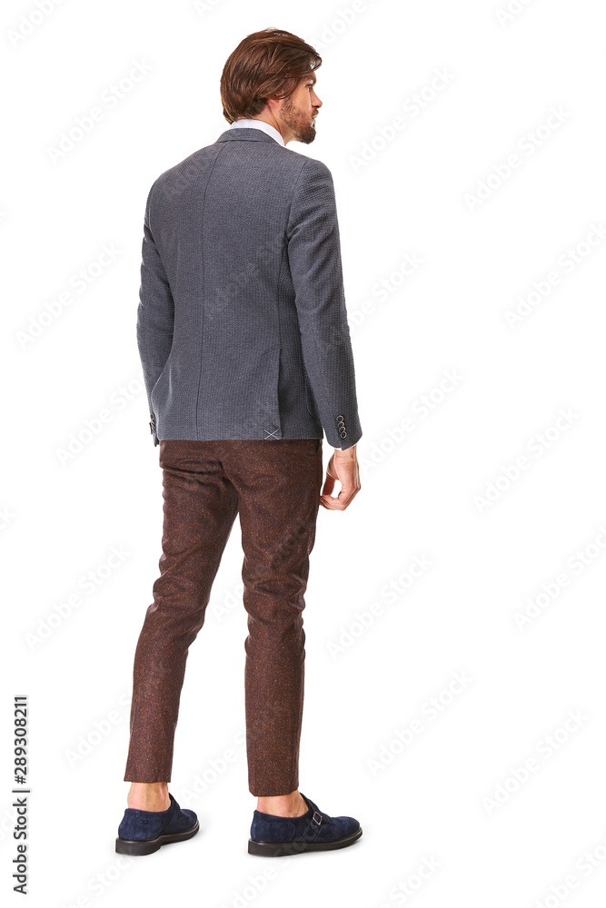 man with beard and dark hair stands back on a white background in dark grey stripped jacket brown trousers and white shirt he has a gold watch on his arm and blue sueded shoes. man with beard and dark hair stands back on a white background in dark grey stripped jacket brown trousers and white shirt he has a gold watch on his arm and blue sueded shoes.
