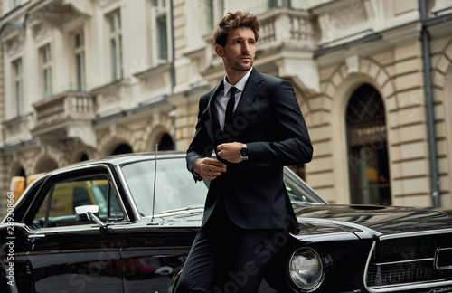 Young handsome man with black classic car wear black suit