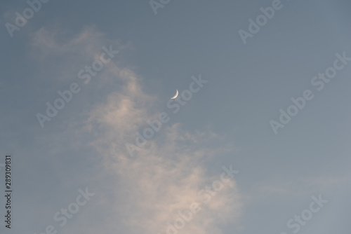 a new moon in the dusk sky and white clouds © bqmeng
