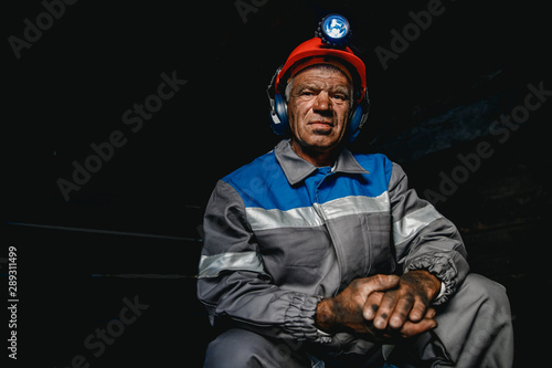 Portrait miner coal man in helmet with lantern in underground mine. Concept industrial engineer photo