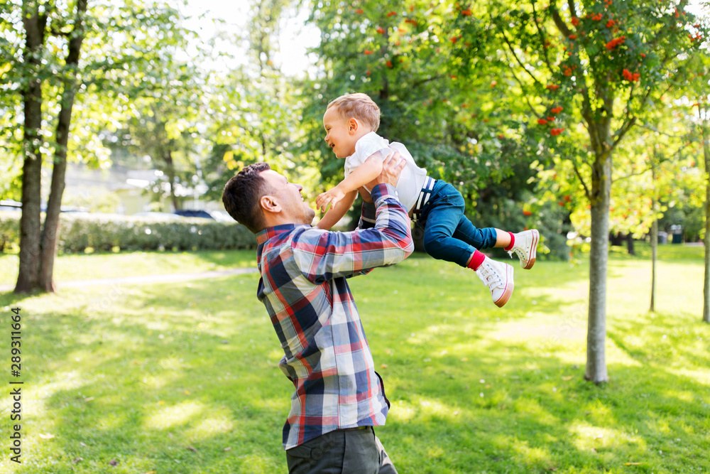 family, fatherhood and people concept - happy father with little son playing in summer park