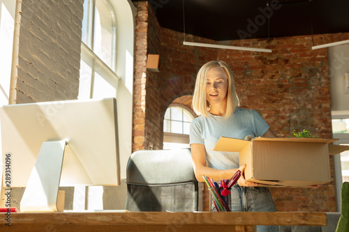 A young businesswoman moving in the office, getting new work place. Young caucasian female office worker equips new cabinet after promotion. Looks happy. Business, lifestyle, new life concept. photo