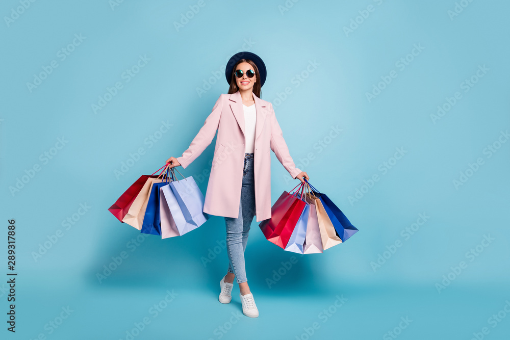 Full size photo of lovely funny girl on her weekends go shopping buy presents souvenirs wear vintage season coat denim jeans eyeglasses eyewear isolated over blue background Full size photo of lovely funny girl on her weekends go shopping buy presents souvenirs wear vintage season coat denim jeans eyeglasses eyewear isolated over blue background