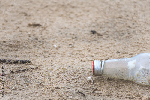 Glass bottle trash dropped on the beach environmental pollution.