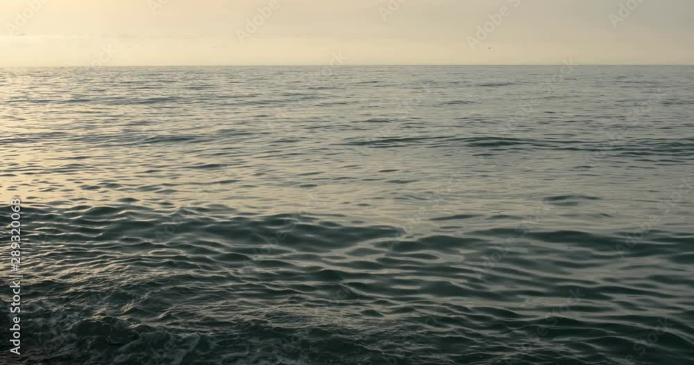 Sealine on the pebble beach with waves of rock stones during the sunset when sun goes down to sea Sealine on the pebble beach with waves of rock stones during the sunset when sun goes down to sea