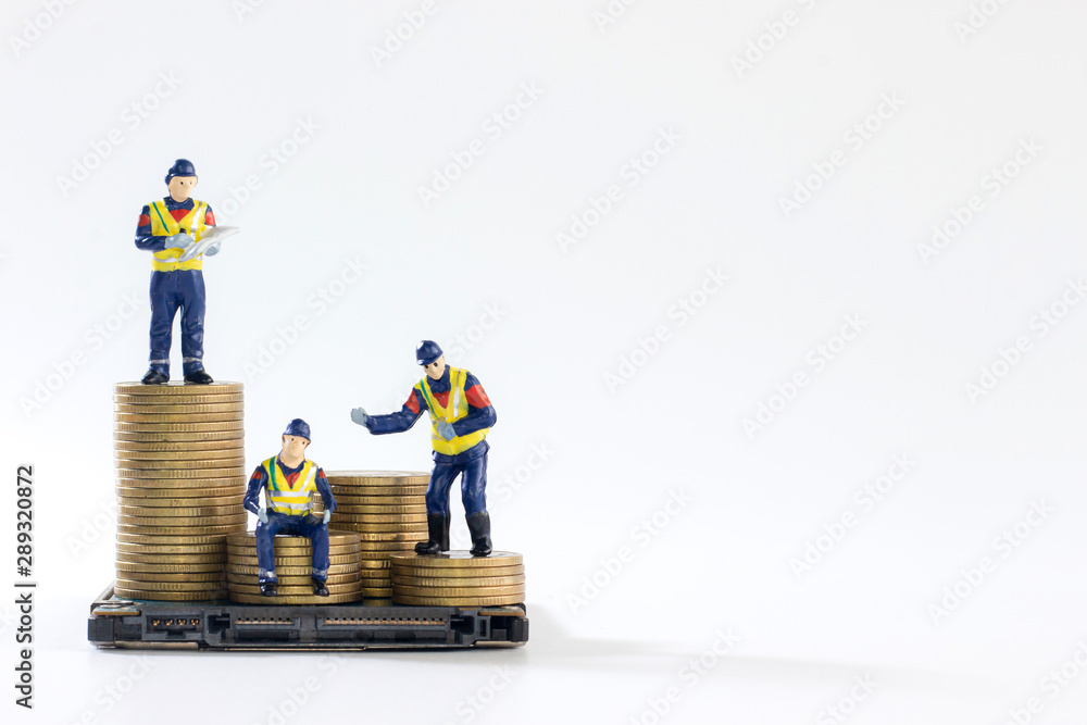Obraz premium Miniature workers are sitting and standing on a pile of golden coins isolated on white background