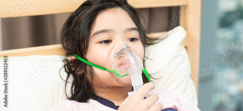 Young asian girl holding inhalation mask by herself at home for allergy treatment.