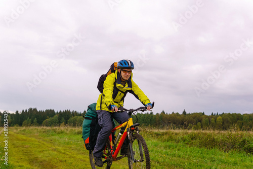 bikepacker rides on a dirt road through a field