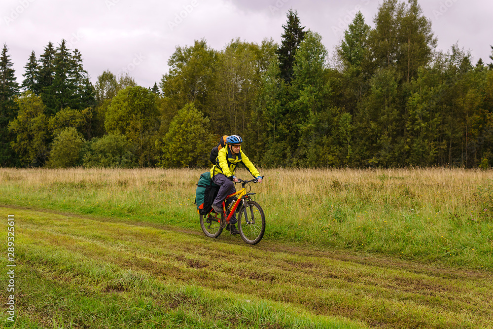 cycling tourist rides on a dirt road through a field