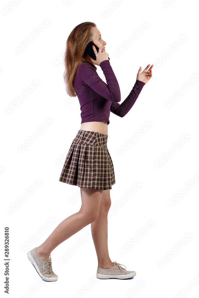 side view of a woman walking with a mobile phone. side view of a woman walking with a mobile phone.