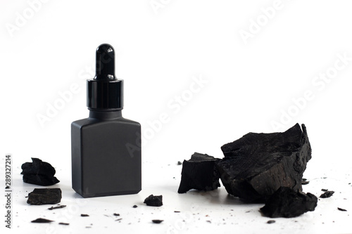 Black serum bottle with charcoal on white background, Mockup product