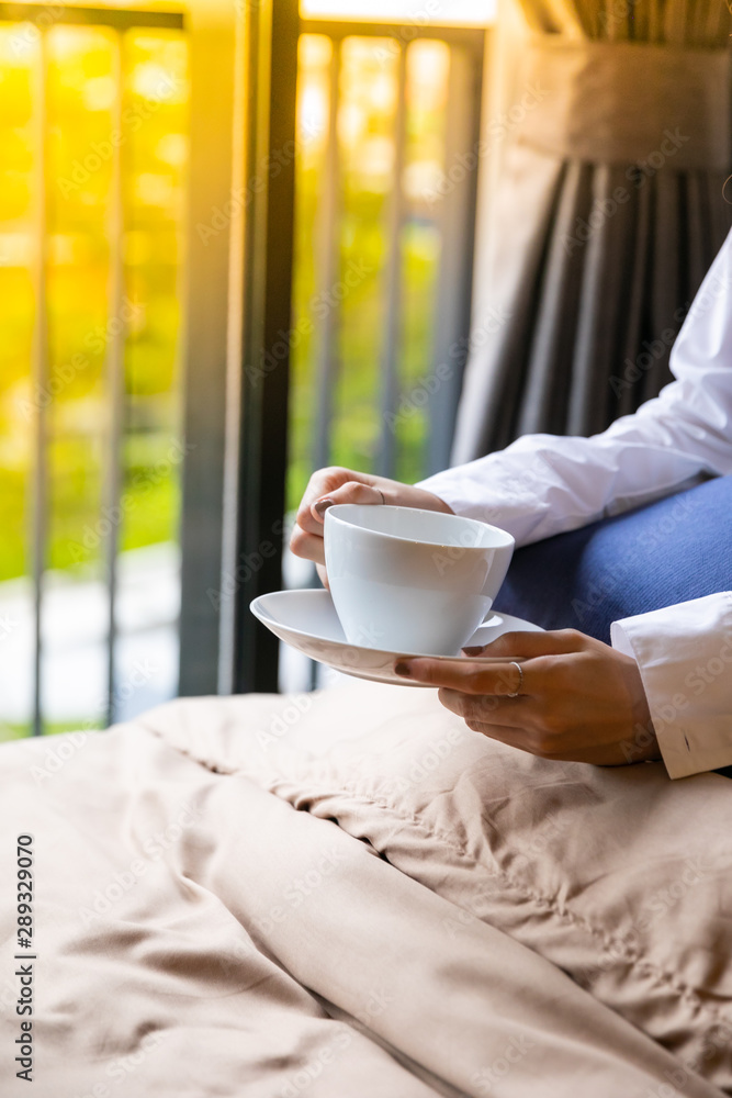 Coffee in bed. Close up of woman having morning coffee while lying on the bed at home. Happy cheerful relaxing Coffee in bed. Close up of woman having morning coffee while lying on the bed at home. Happy cheerful relaxing